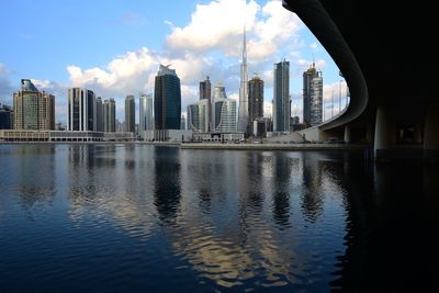 Bridge over river by burj khalifa and modern buildings against sky