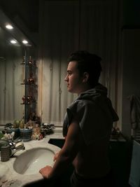 Side view of young man standing in bathroom