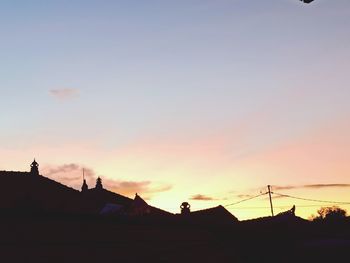 Silhouette houses and buildings against sky during sunset