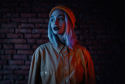 Portrait of young woman standing against wall