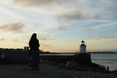 Woman on beach against sky during sunset