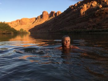 Portrait of woman swimming in river against sky