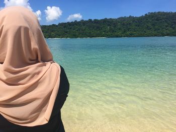 Rear view of woman wearing hijab at beach against sky