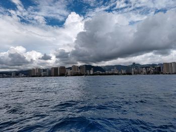 Sea by buildings against sky in city