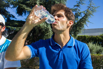 Young man drinking water outdoors