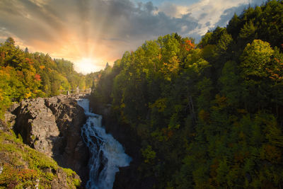 Scenic view of waterfall against sky during sunset