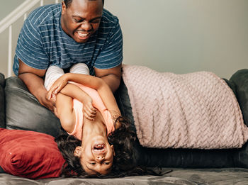 Father and kids at home playing on couch, african american or black father with his children