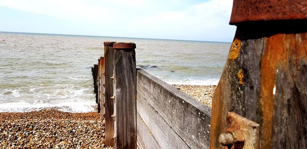 Wooden posts on beach against sky
