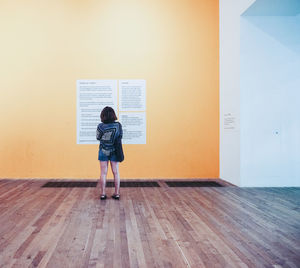 Rear view of woman standing against wall