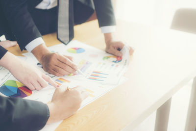 Close-up of business colleagues discussing over documents in office