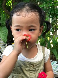 Close-up of cute girl smelling red flower