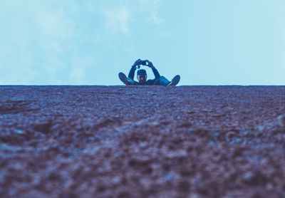 Low angle view of man sitting on wall