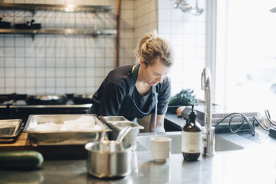 Mature female chef working by kitchen counter in restaurant