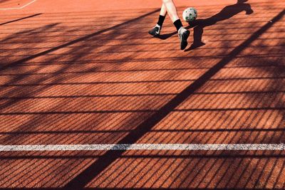 Low section of man playing soccer on field during sunny day