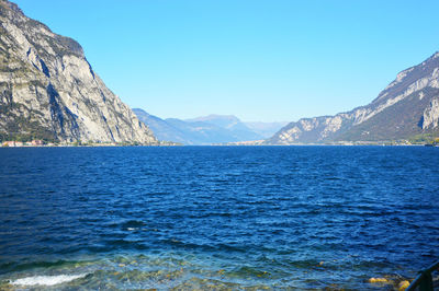 Scenic view of sea and mountains against clear blue sky