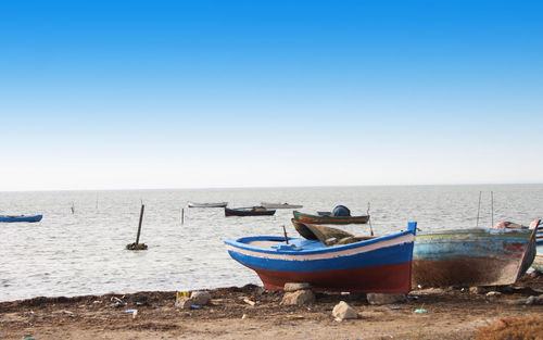 Boat moored on shore against clear sky