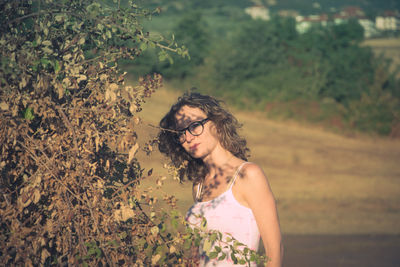 Young woman standing by tree