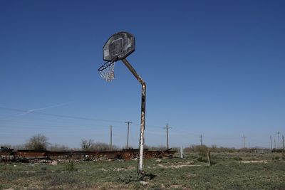 An abandoned run down basketball basket against a blue sky.