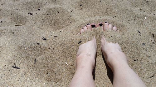 Low section of woman standing on sand