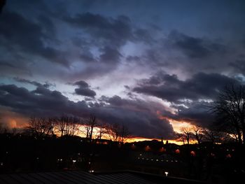 Silhouette of trees against dramatic sky during sunset