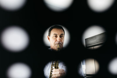 Musician playing saxophone seen through musical stand