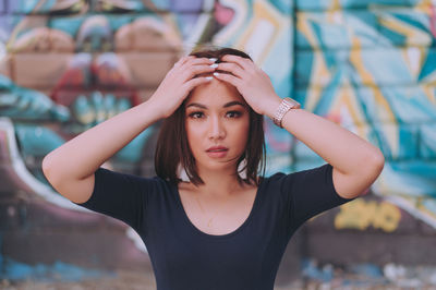 Portrait of beautiful young woman standing against wall