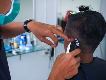 Cropped hands of hairdresser cutting man hair