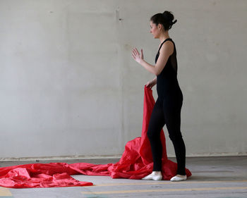 Young woman doing ballet dance with red fabric