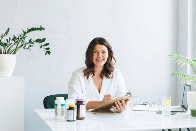 Young woman doctor nutritionist plus size in white shirt working at laptop at modern bright office 