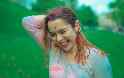 Smiling young woman with colorful powered paints during holi