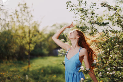 Young woman standing against trees