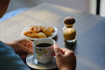 Man holding coffee cup and spoon on table