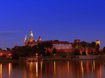 Royal wawel castle illuminated at night reflecting in the vistula river, krakow - poland
