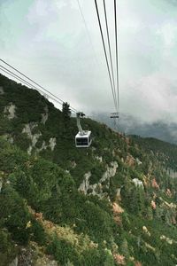 Electricity pylon on mountain against cloudy sky