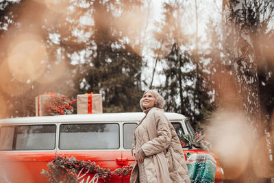 Portrait of smiling young woman sitting on car