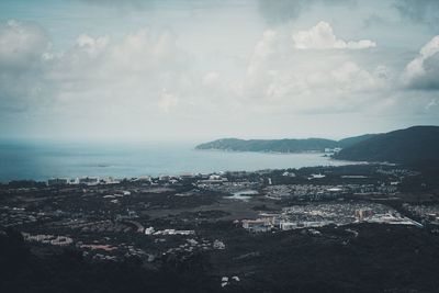 Aerial view of city by sea against sky