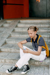 Side view of young man sitting on footpath