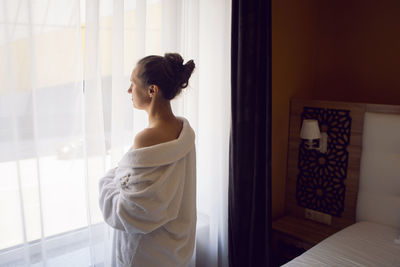 Side view of young woman looking away at home