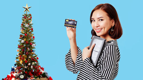 Portrait of smiling young woman holding christmas tree