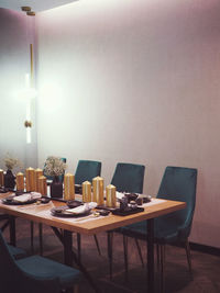 Empty chairs and table against illuminated wall