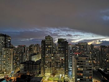 Illuminated buildings in city against sky at night