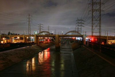 Illuminated railroad tracks against sky in city at night