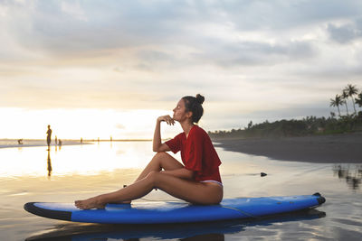 Full length of woman sitting on paddleboard