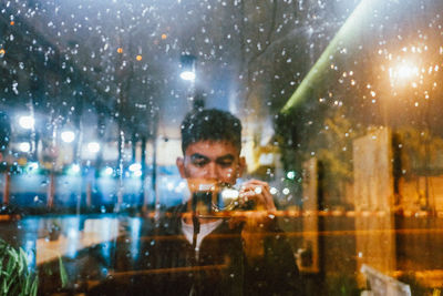 Portrait of man using mobile phone at window