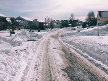 Snow covered field by houses against sky