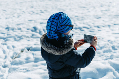 Man photographing with mobile phone in snow