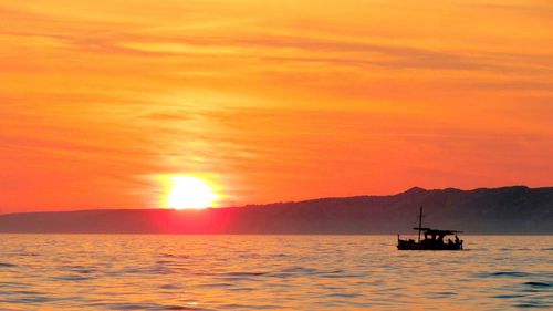 Boats sailing in sea at sunset