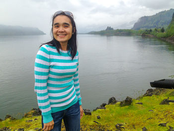 Portrait of smiling woman standing by lake