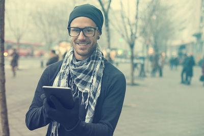 Portrait of young man using mobile phone in city