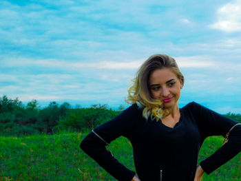 Portrait of smiling young woman standing against sky